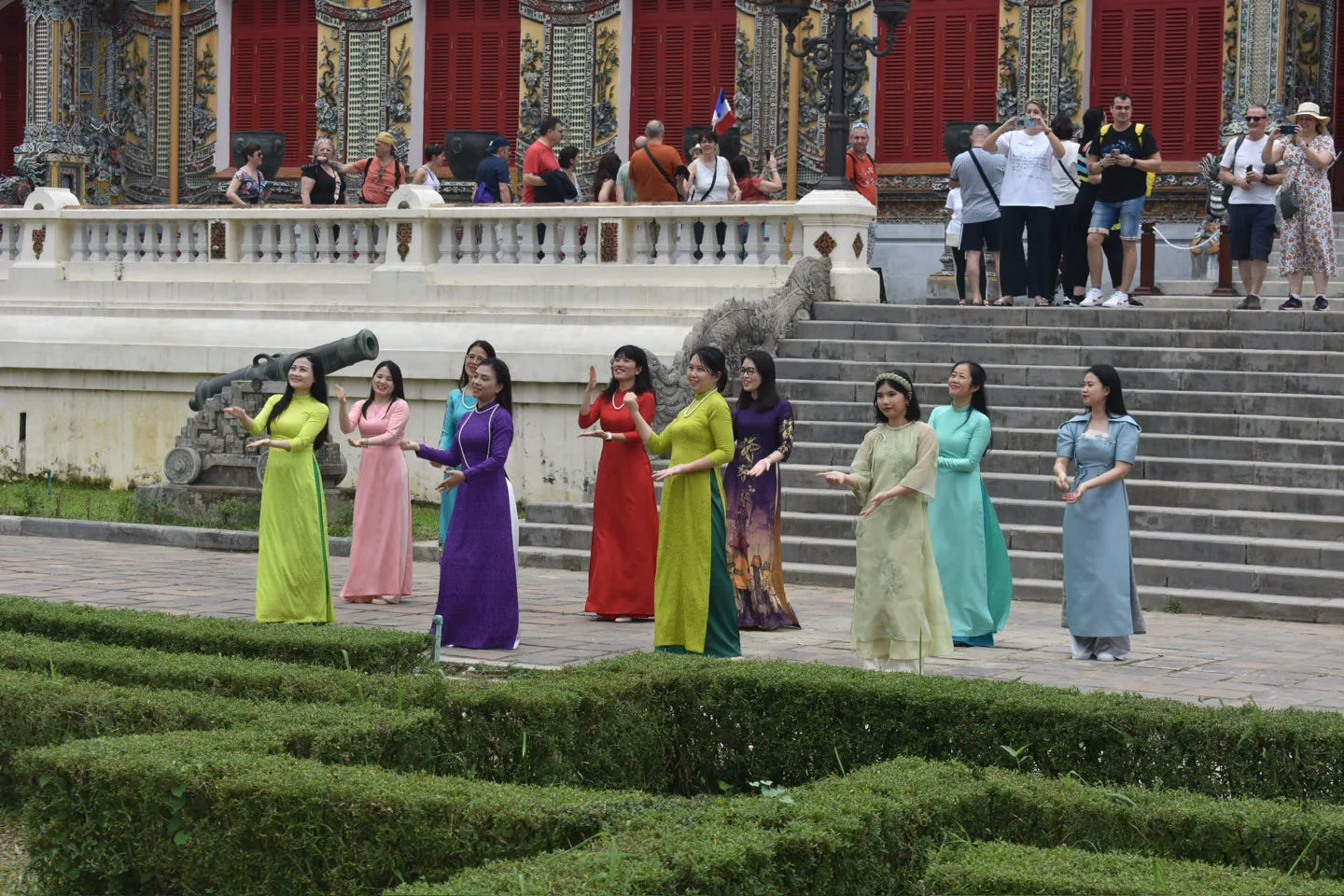 Vrouwen in traditionele ao dai jurken poseren bij de keizerlijke stad in Hue