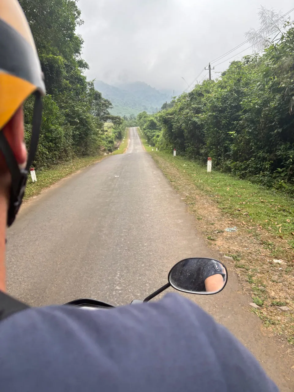 Scooter POV op een rechte weg door de jungle in Phong Nha nationaal park